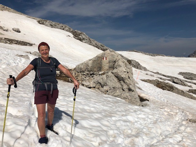 A photo of Bernie Dwyer in the Dolomites, standing on a snowy mountain in hiking gear.