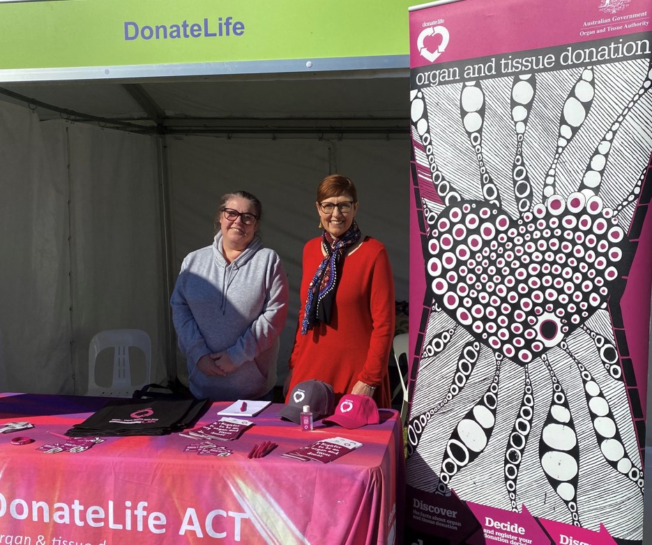 Two women stand behind a DonateLife stand at an event.