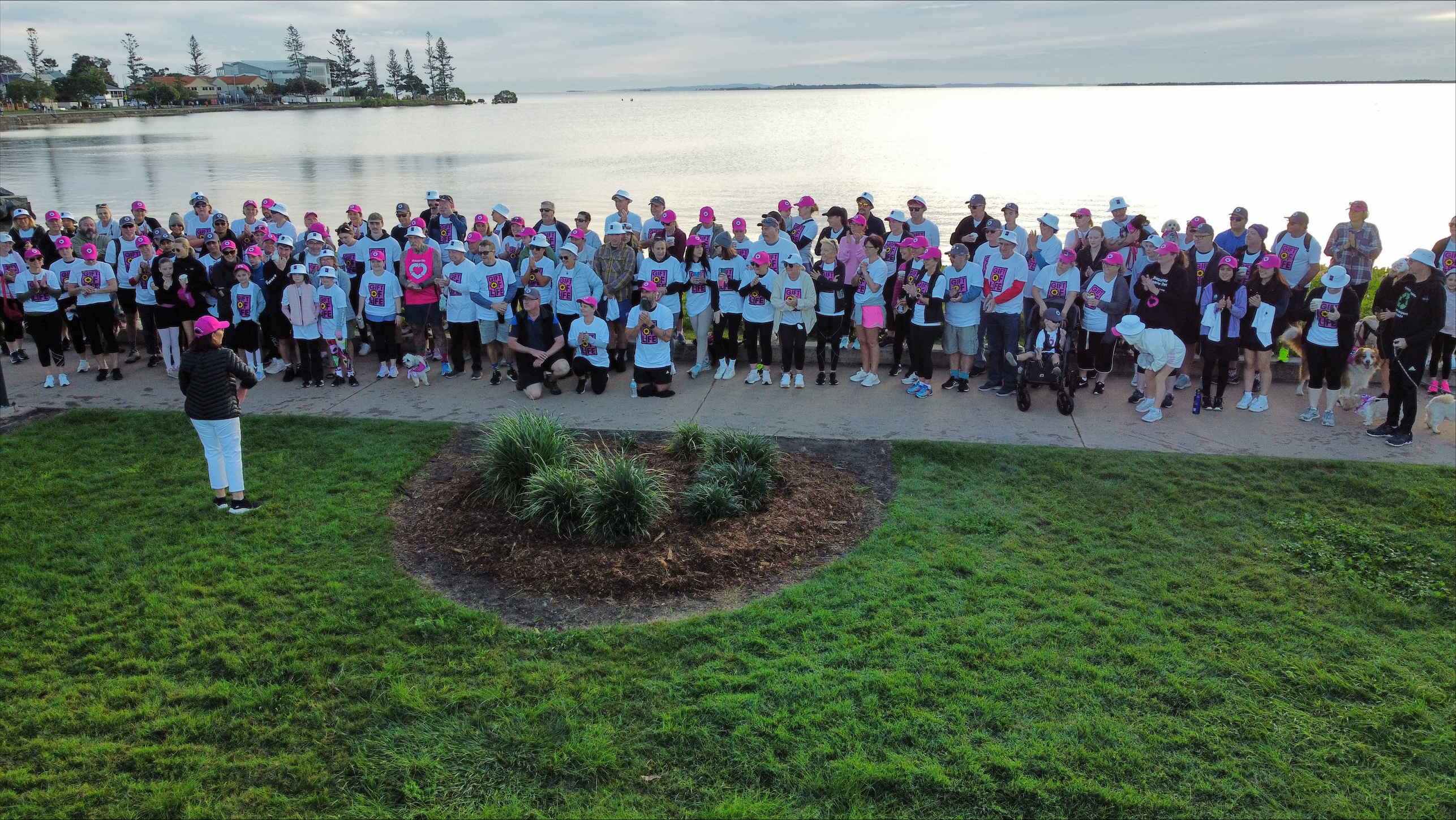 A crowd of people dressed in Gift of Life and DonateLife merchandise gather in front of a large body of water.