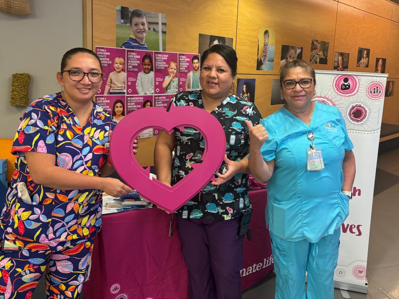 Three female nurses hold up a wooden cut out of the DonateLife logo.