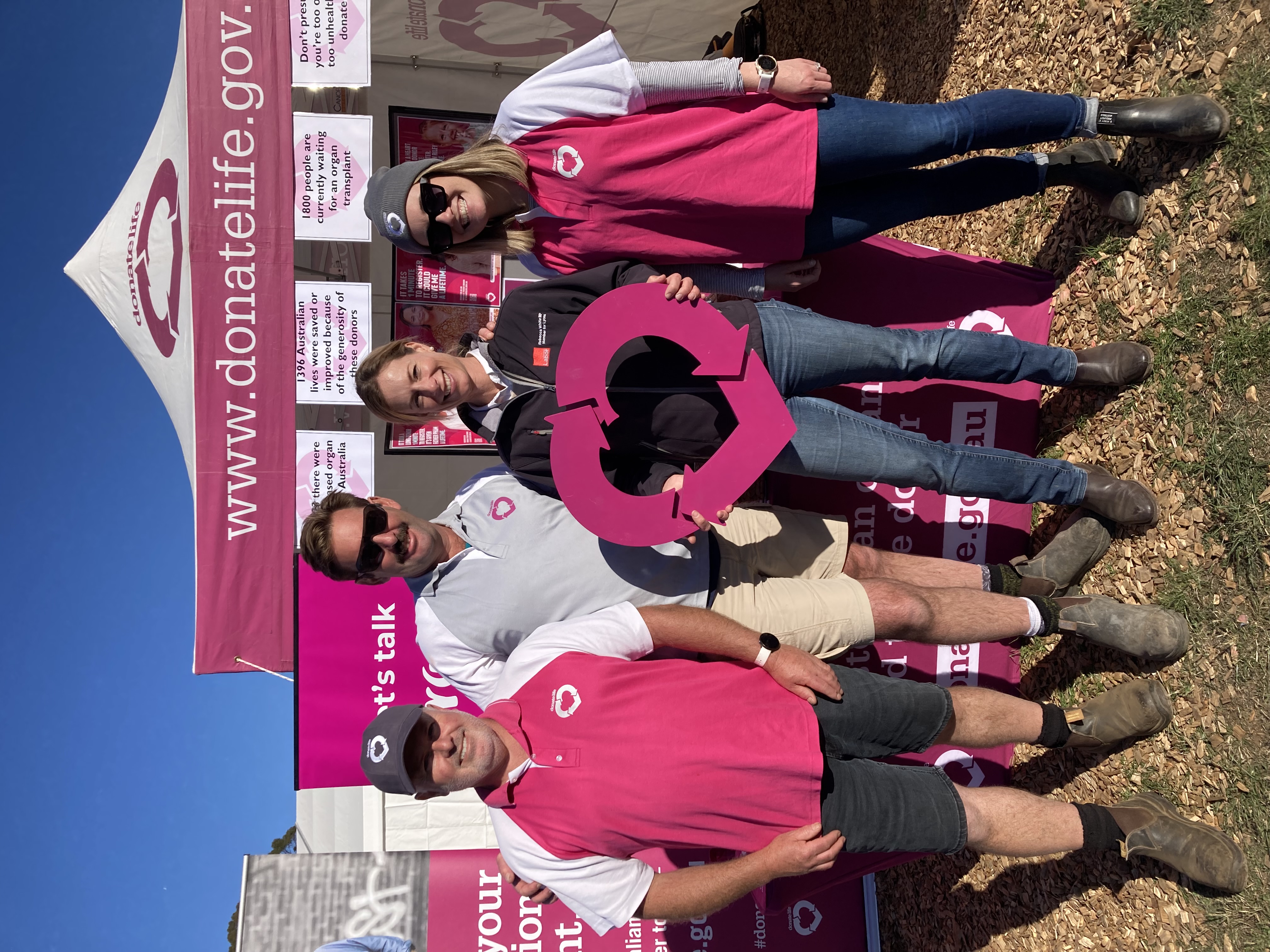 Four adults pose for a photo in front of a DonateLife themed stand.