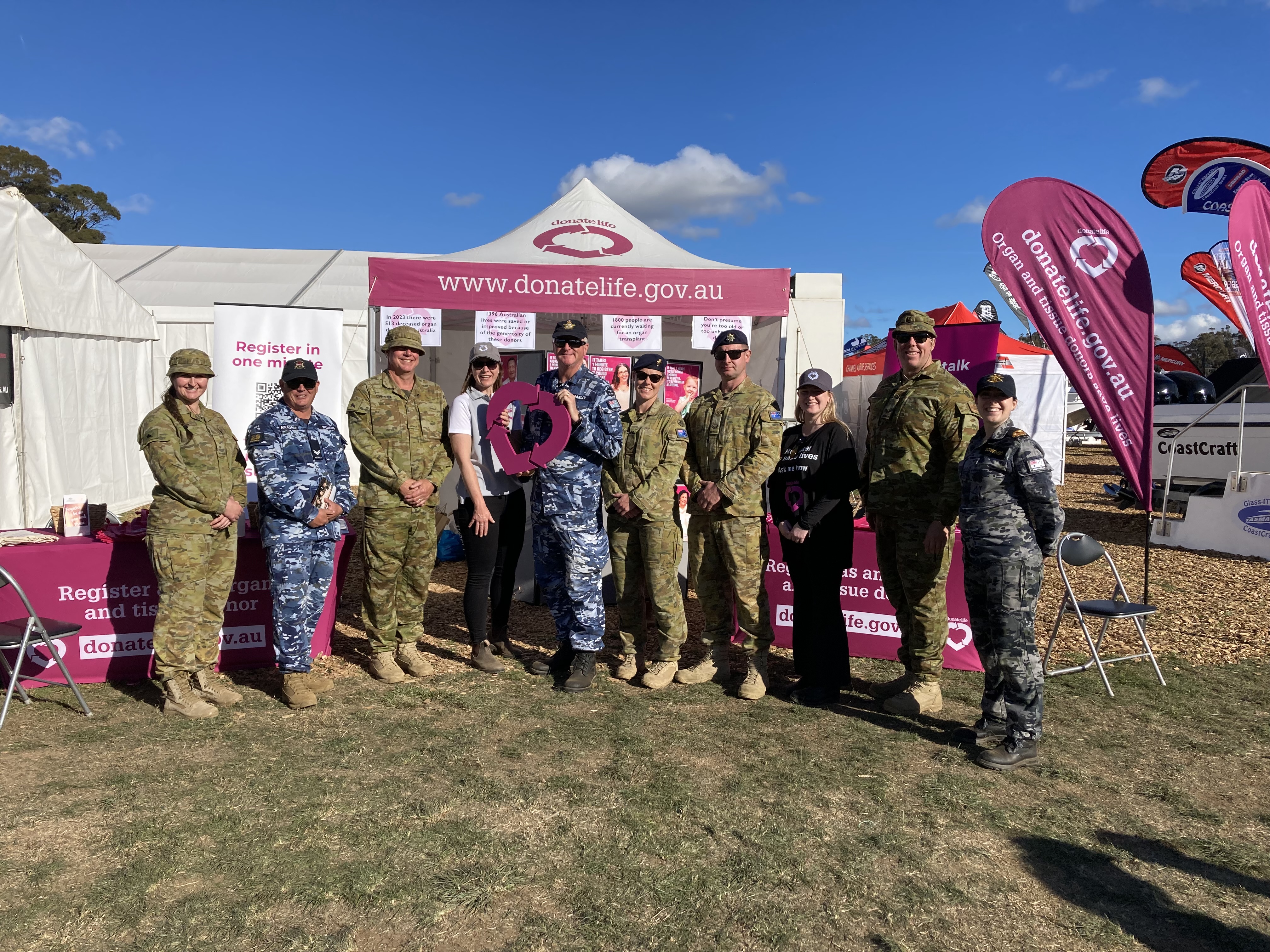 A group of adults posing for a photo in front of a DonateLife stand.