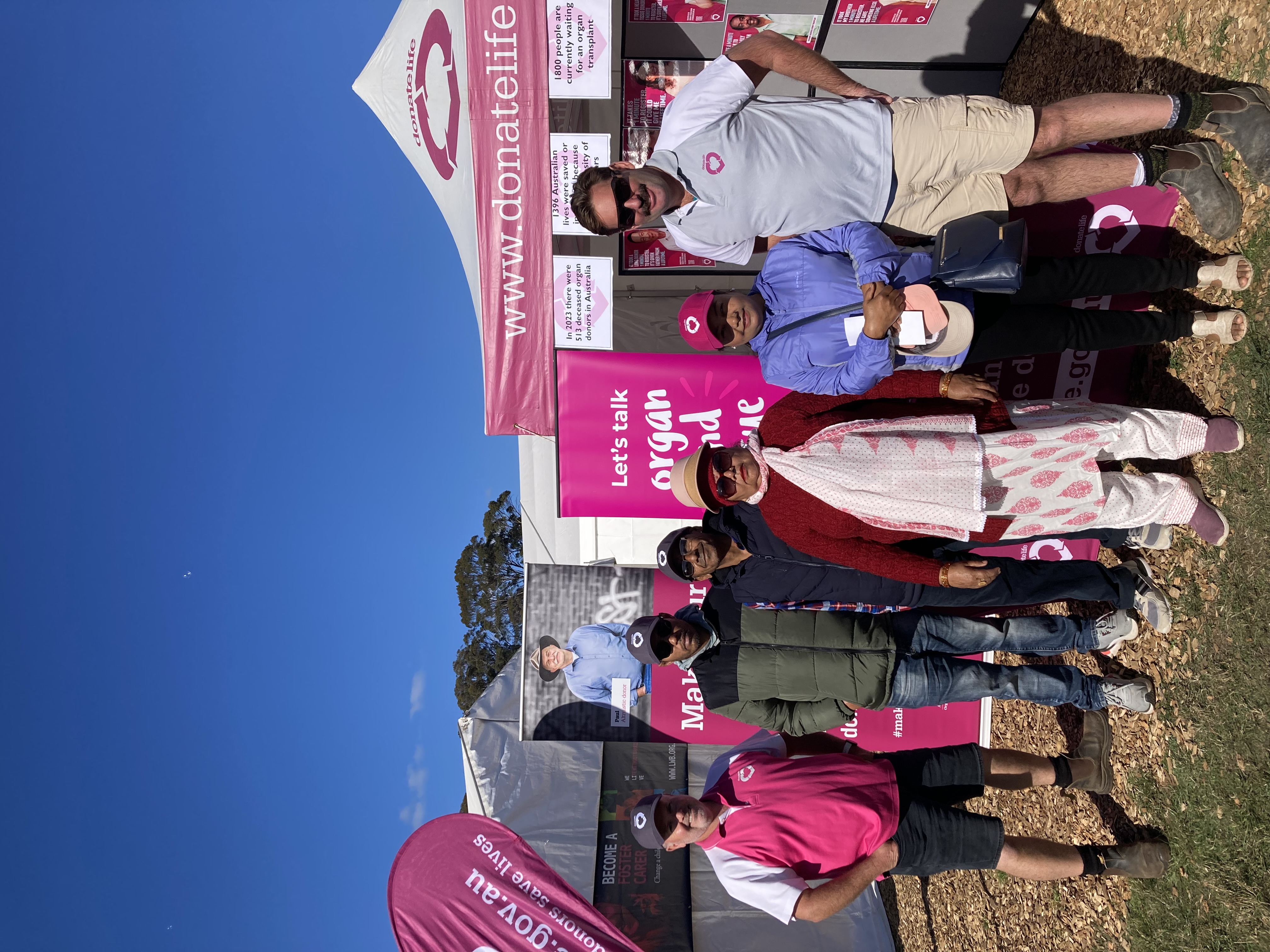 A group of adults posing for a photo in front of a DonateLife stand.