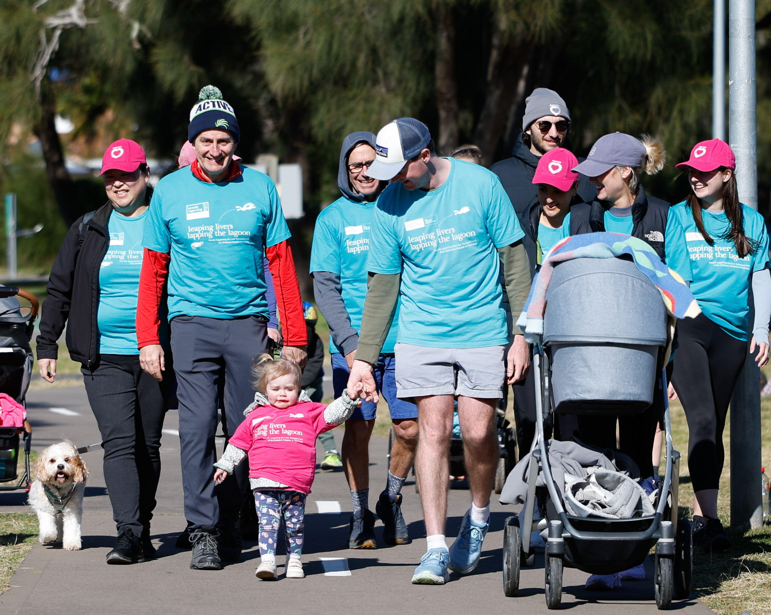 A group of attendees at the Leaping Livers event for DonateLife Week stroll down a path, pushing a baby stroller among them.