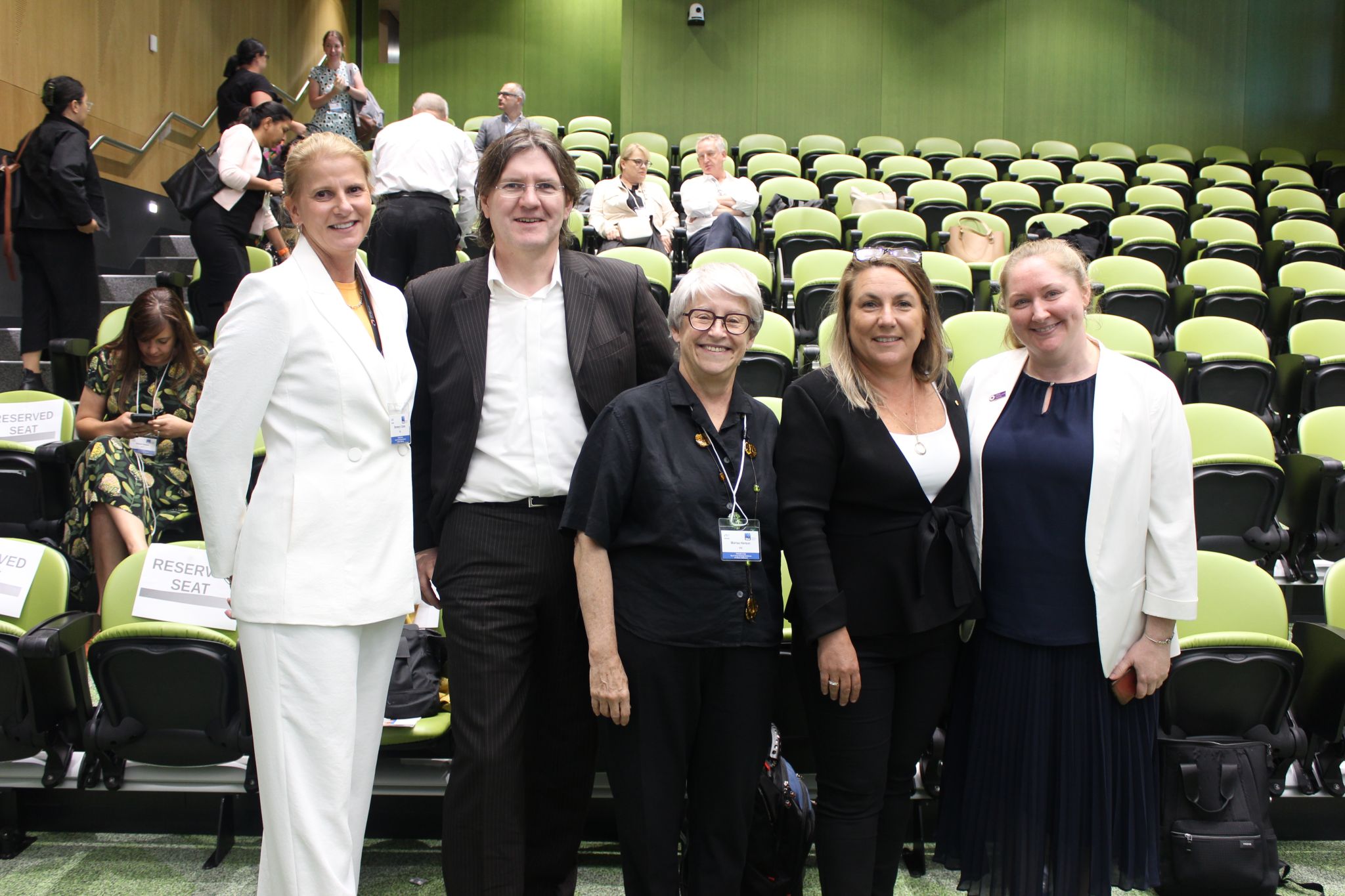 Five people standing in an auditorium smiling for a group photo.