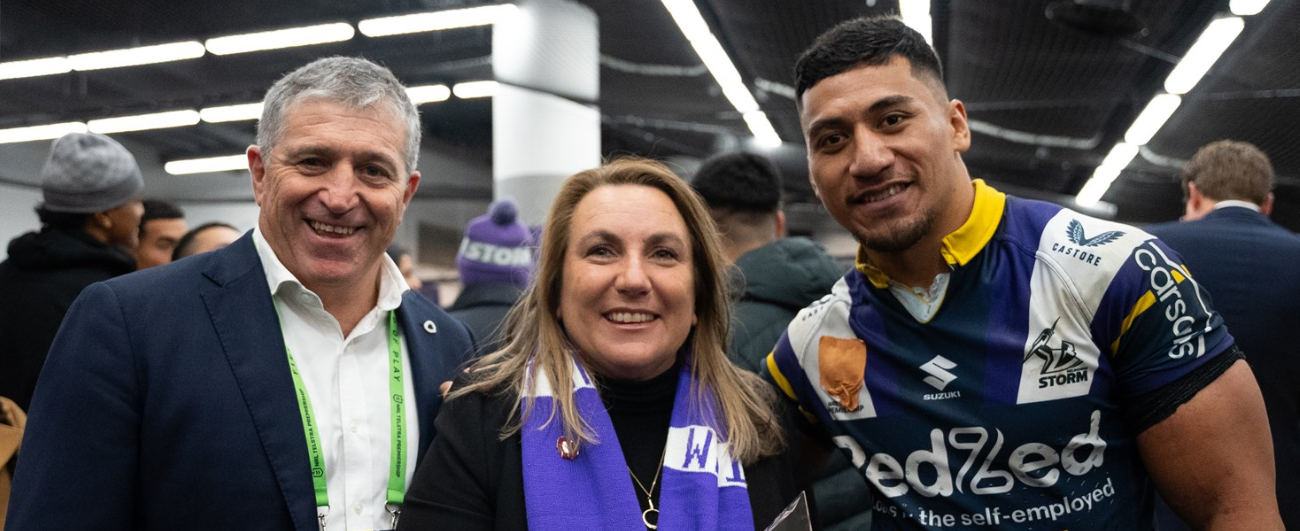 Photo of OTA CEO Lucinda Barry wearing a Melbourne Storm scarf with two Melbourne Storm players