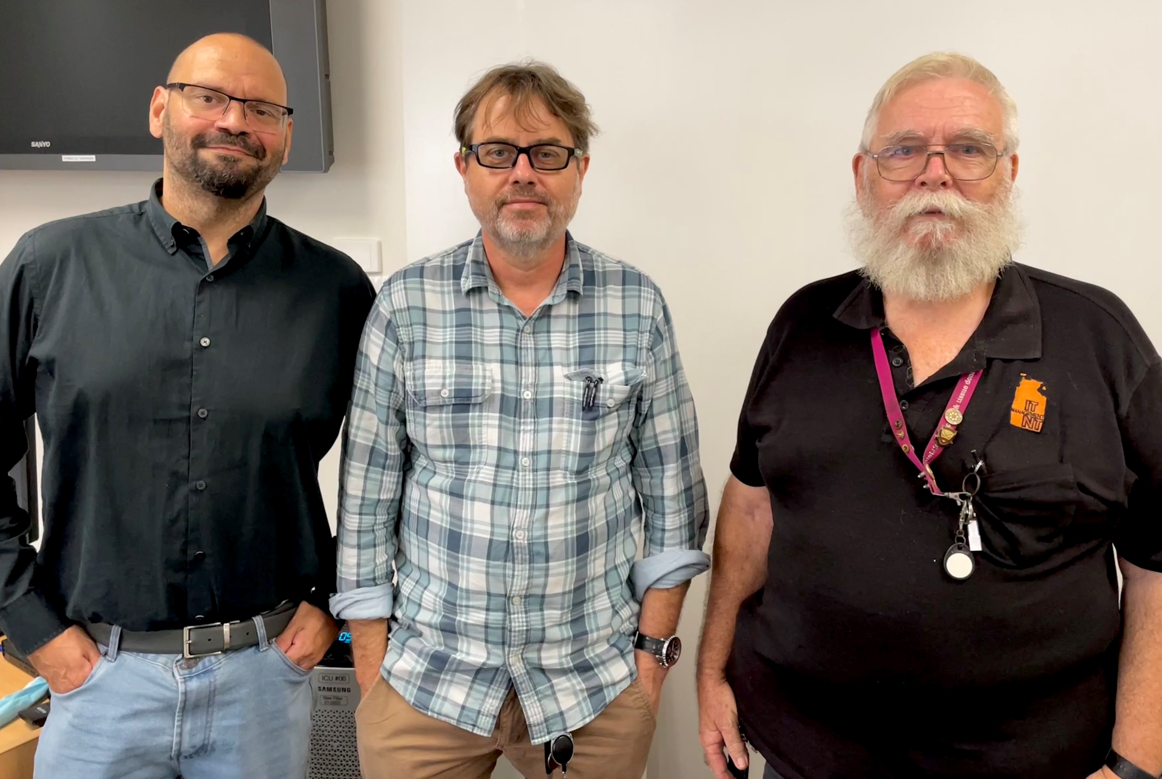 Three men standing together for a photo.