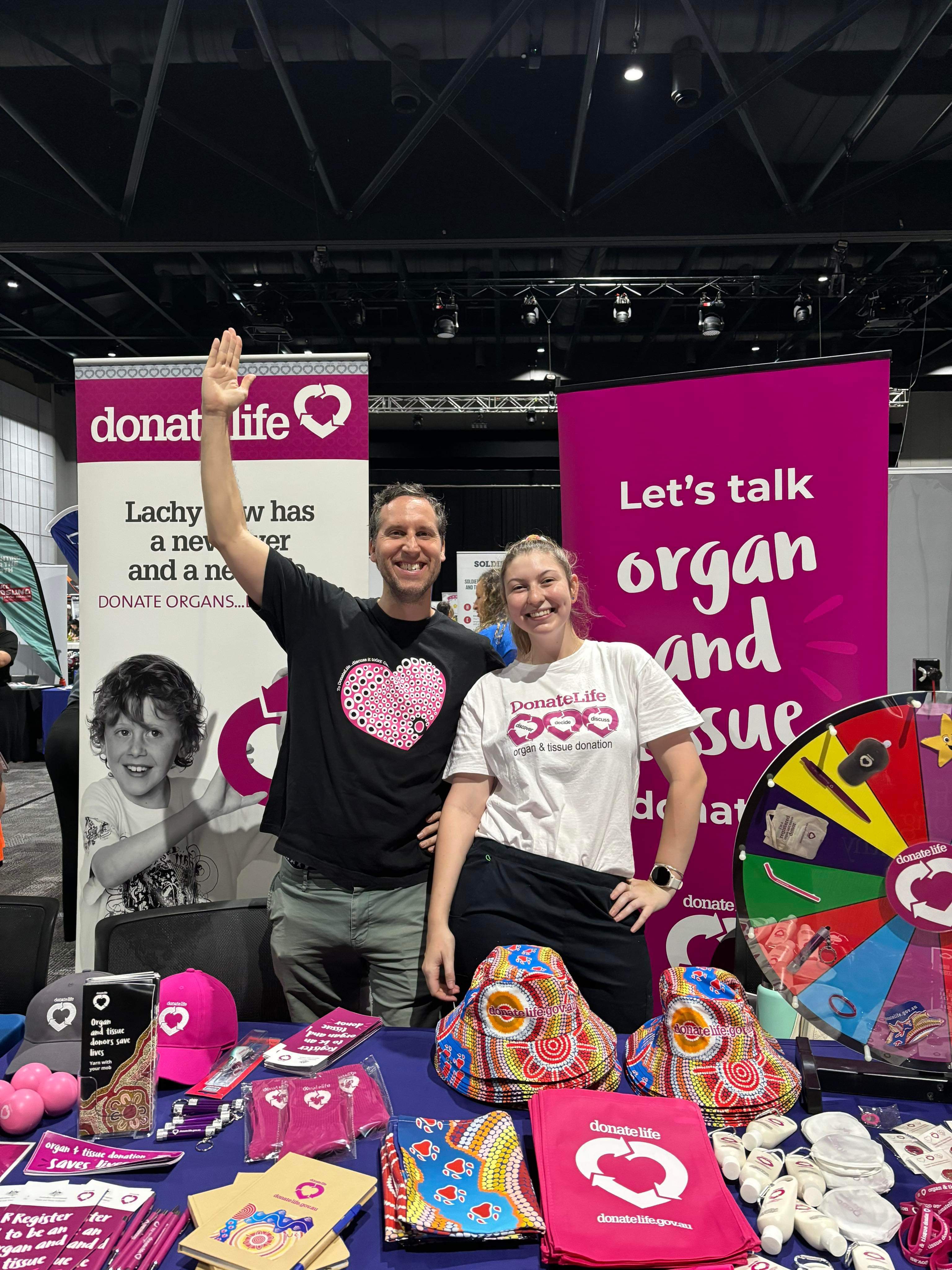 Two DonateLife staff members behind a DonateLife stall, smiling at the camera.