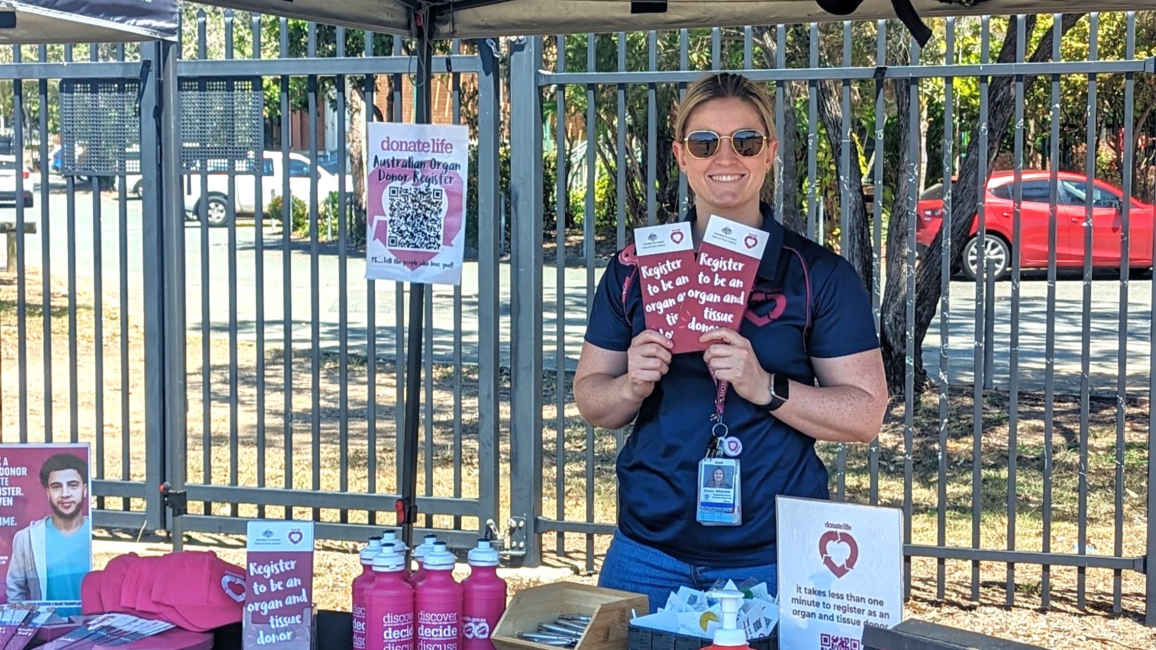 A person at a DonateLife stand holding up brochures and smiling for the camera. 