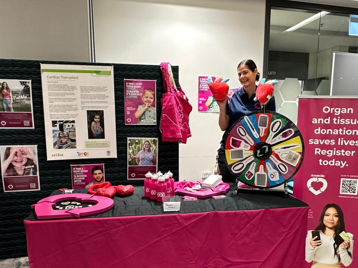 A woman poses with merch at a DonateLife open day stand.