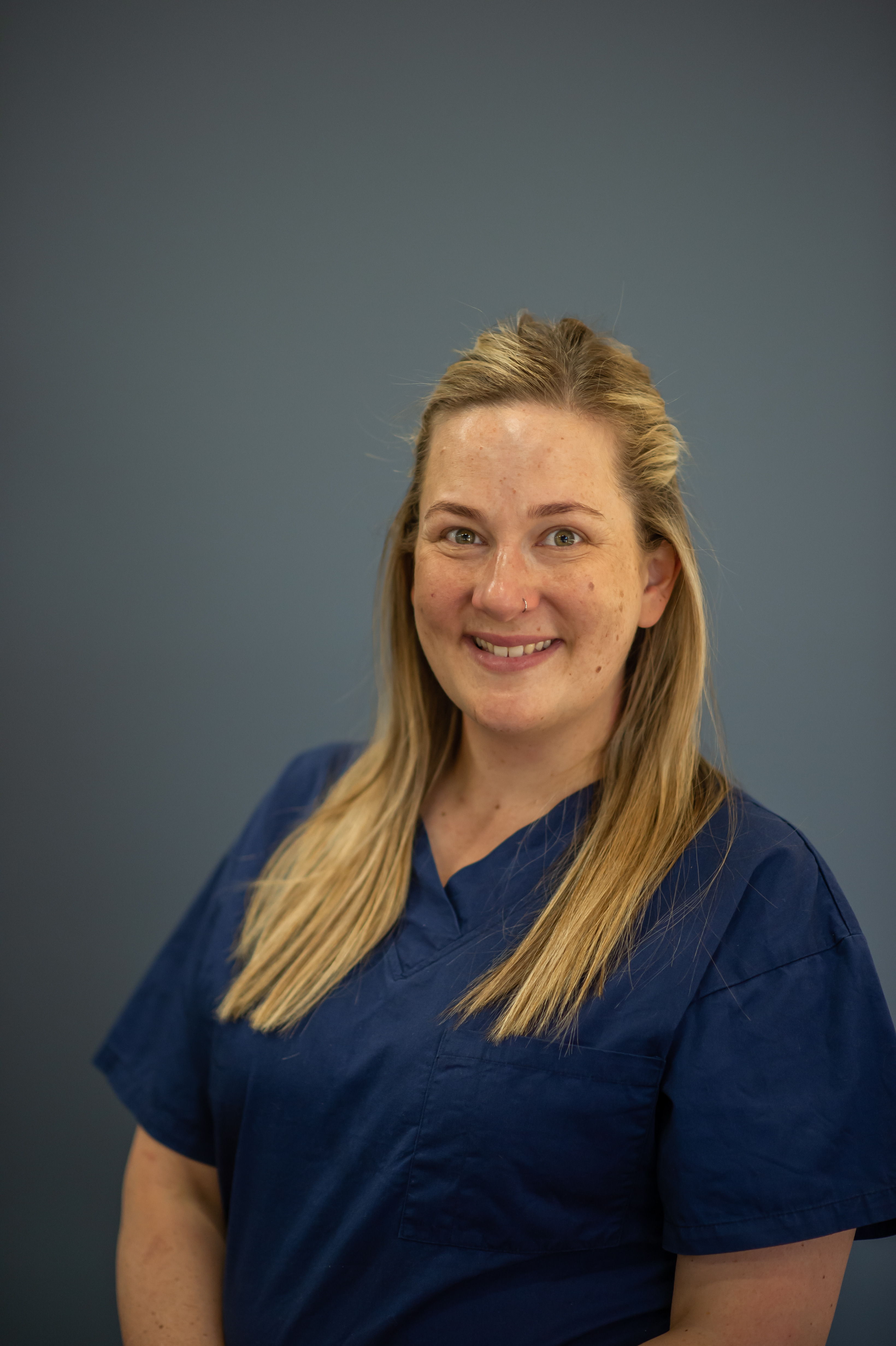 A woman wearing navy blue scubs smiles at the camera.