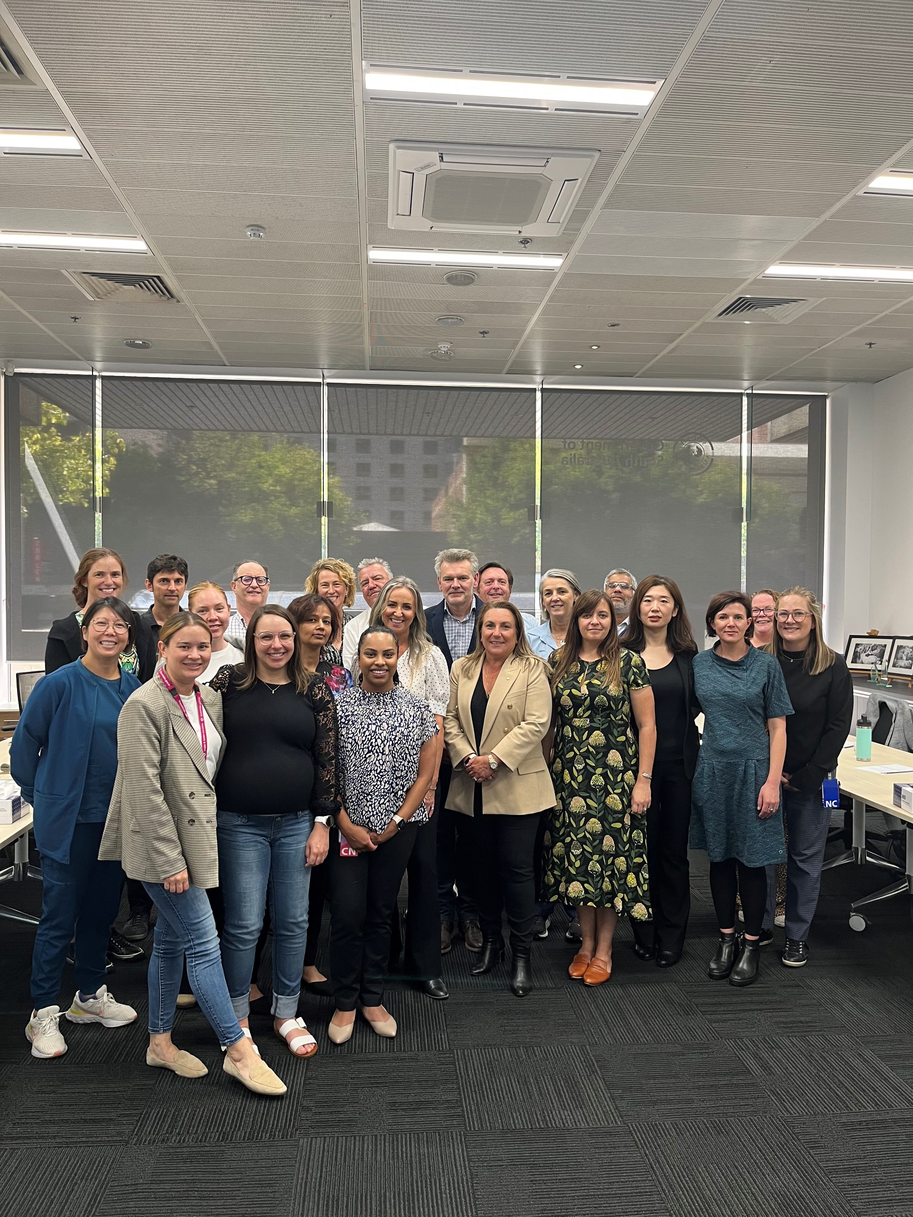 A large group of people inside an office pose for a group photo together.