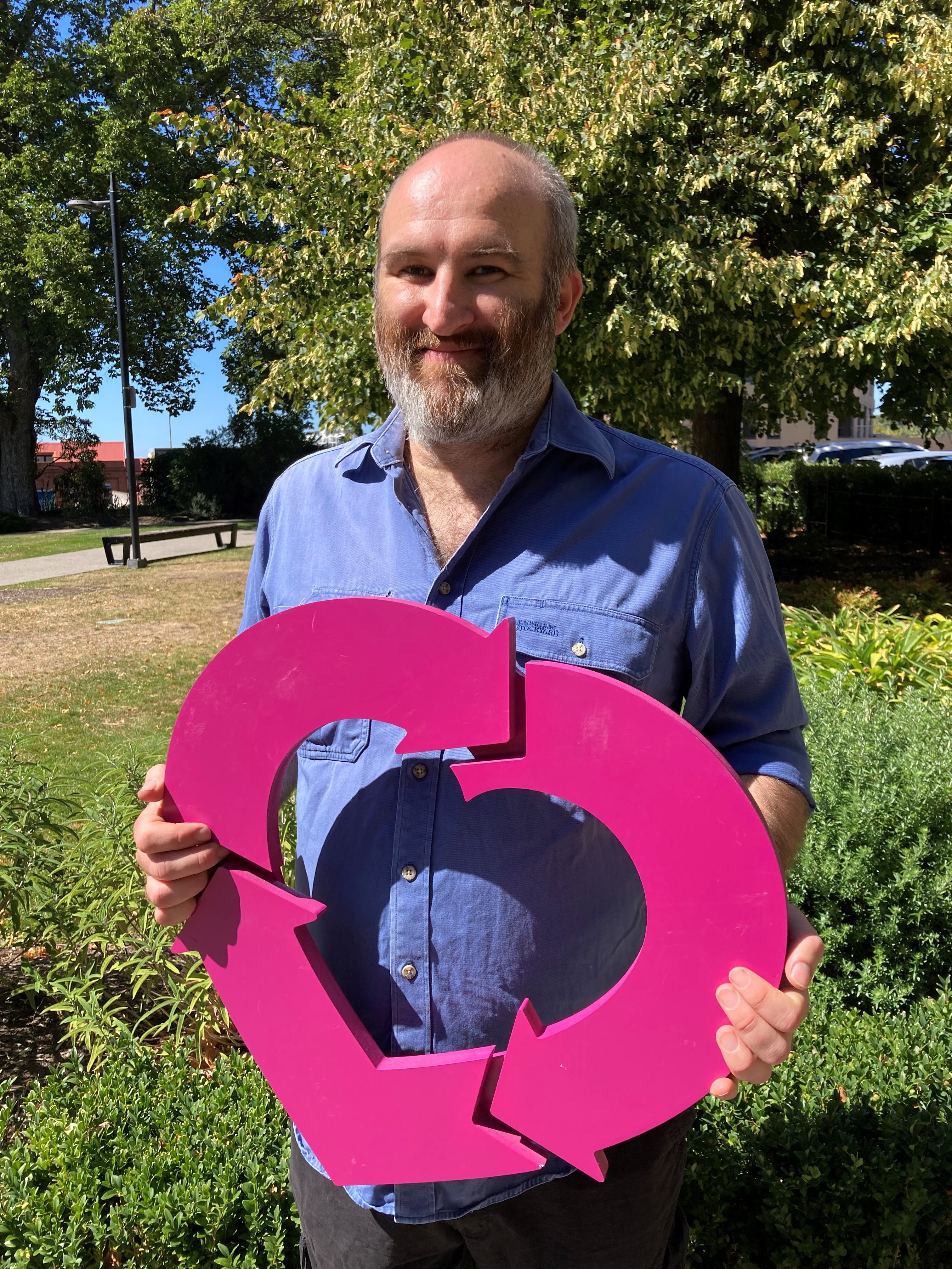 A man stands holding a magenta DonateLife heart, smiling at the camera.