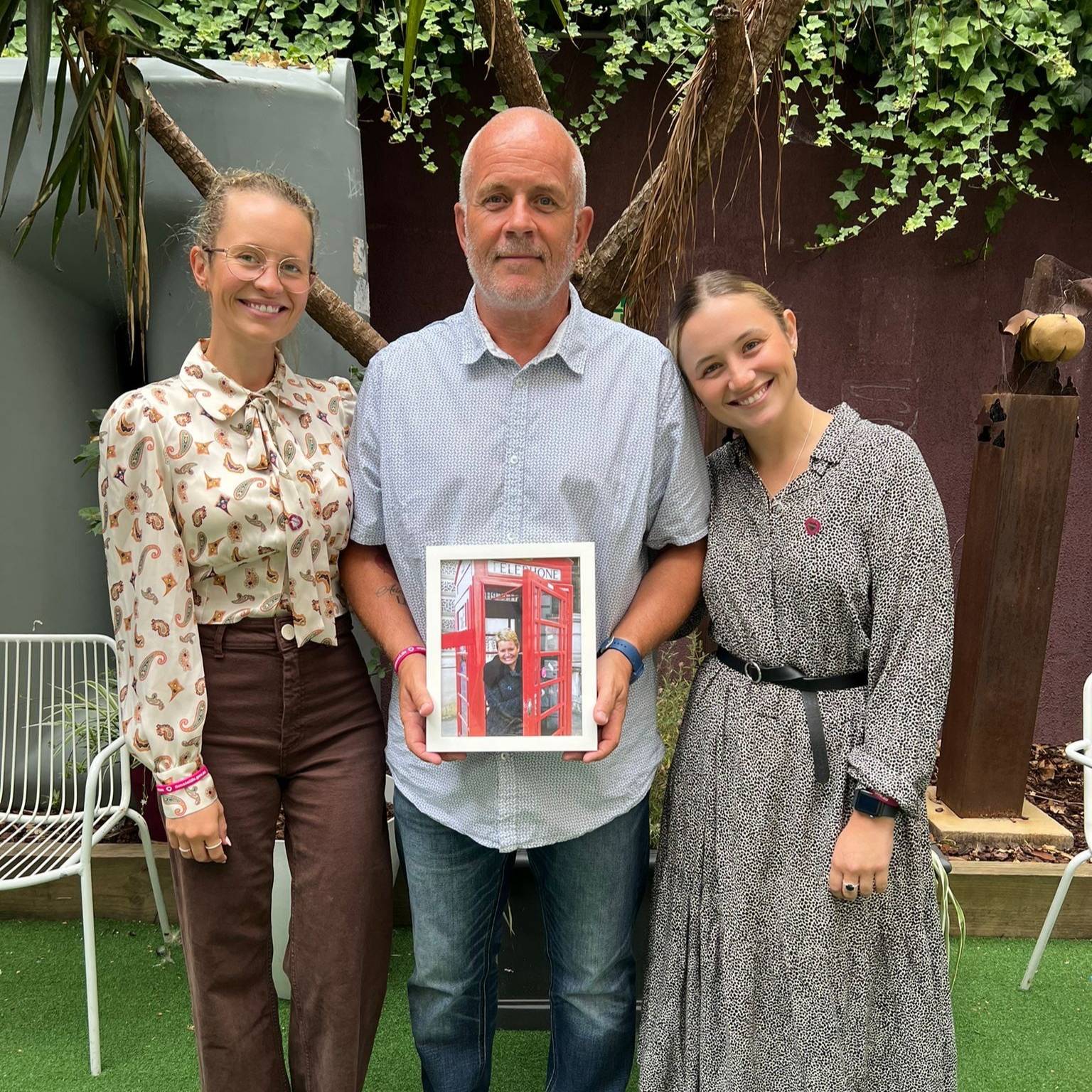 Photo of donor family, Rob Clemmens and his daughters holding a photo of his wife, and their mum Katie