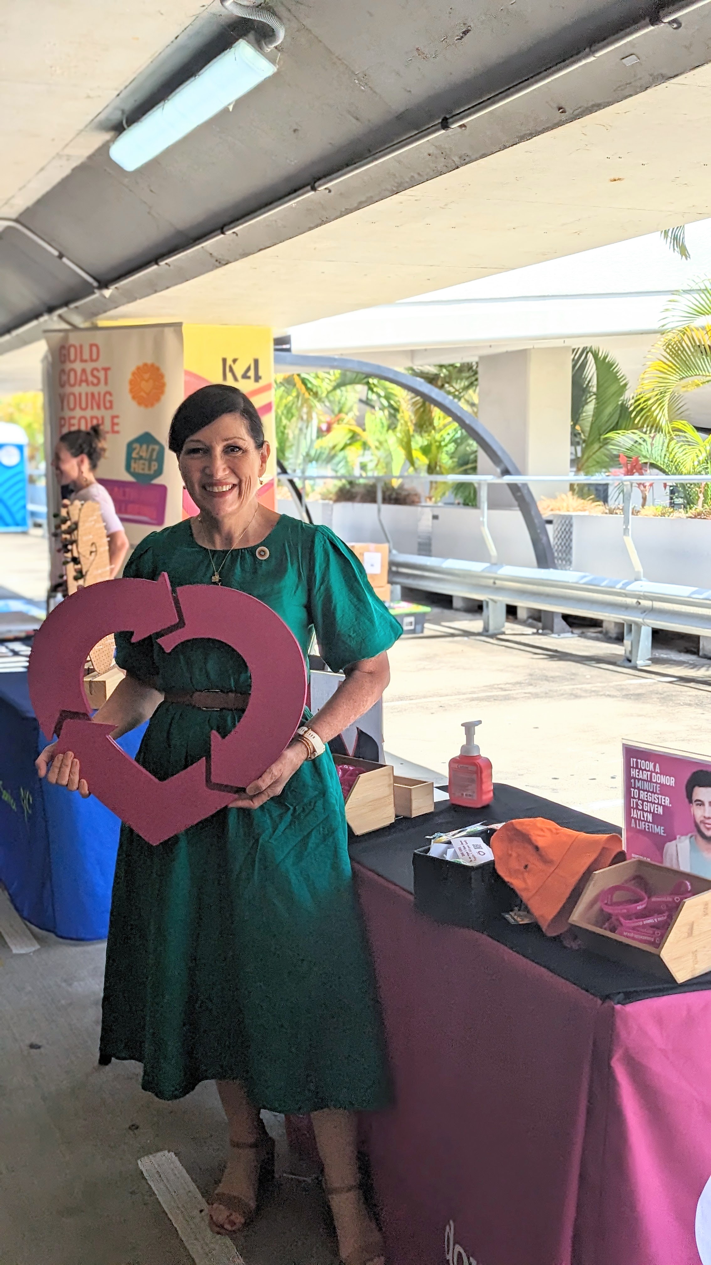 Minister Leeanne Enoch poses with the DonateLife heart logo in front of the Schoolies Registration Day Stall.