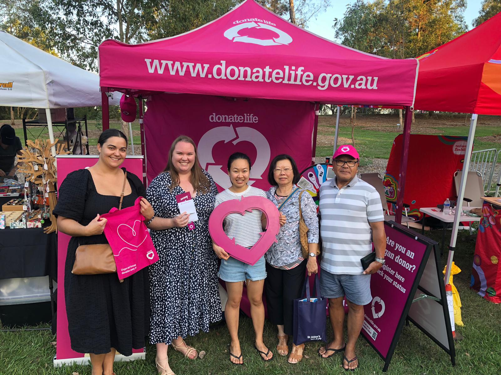 Volunteers and festival attendees pose in front of the DonateLife stall at the Brisbane City Council’s Sherwood Festival.