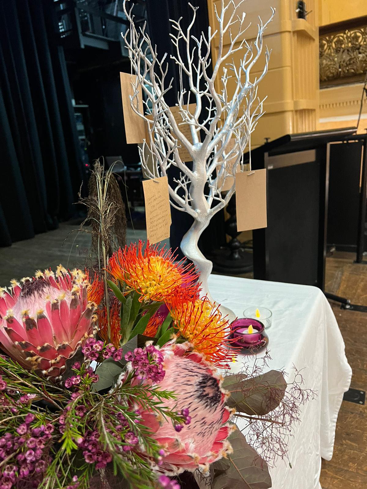 A flower display and a tree with messages at the VIC Service of Remembrance.